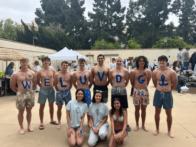 shirtless line spelling WE LUV DG at pool event